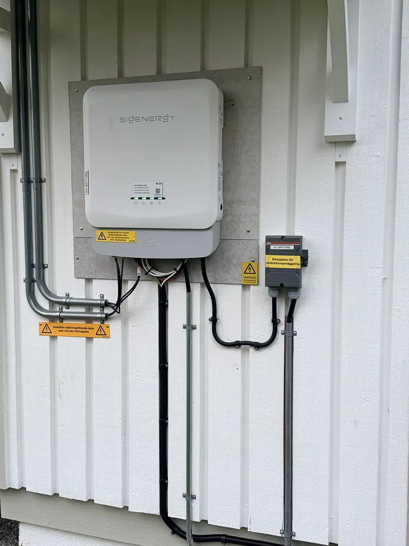 Sigenergy hybridväxelriktare på husfasad med märkta DC- och AC-brytare