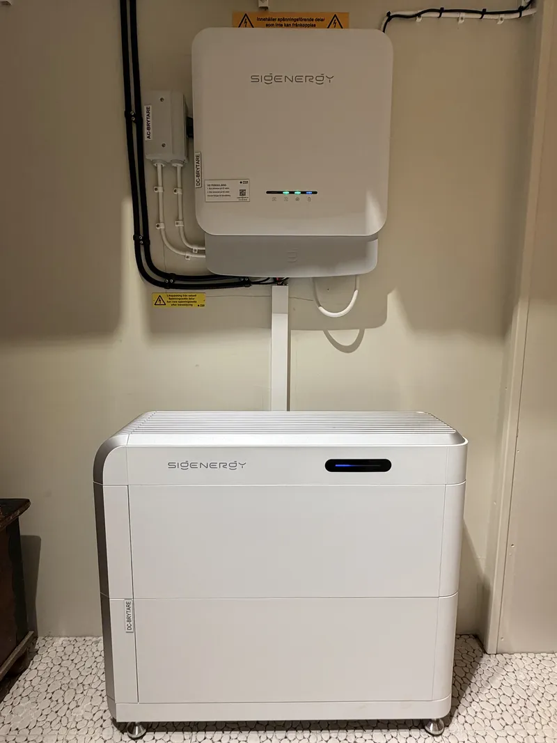 Sigenergy hybridväxelriktare på vägg ovanför ett SigenStor-batteritorn